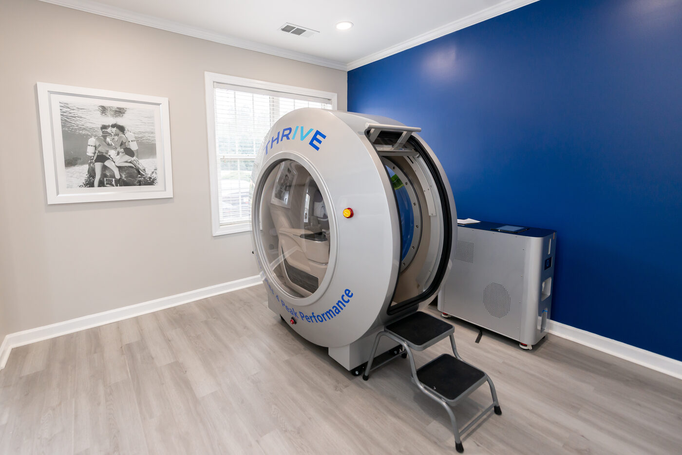 Hyperbaric oxygen therapy suite with THRIVE-branded chamber against blue accent wall